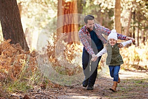Father And Daughter Running Through Fall Woodland