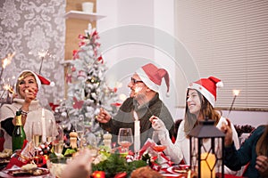 Father and daughter with santa hats playing with hand fireworks at christmas celebration