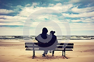 Father and daughter sitting on a bench on the beach