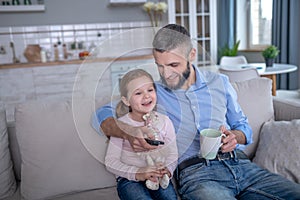 Father and daughter sitting on the couch in a good mood.