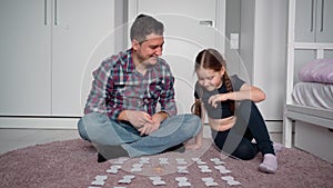 Father and daughter are sitting on the floor in a bright children`s room. They look at the camera and speak to the camera