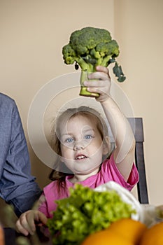 Father and daughter are sitting at the table in the kitchen. Fresh products bought in the store