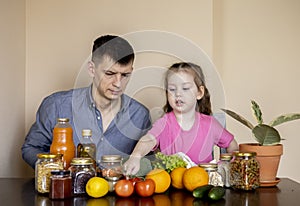 Father and daughter are sitting at the table in the kitchen. Fresh products bought in the store