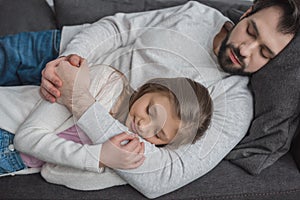 father and daughter sleeping on sofa