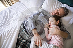 Father and daughter sleeping together on bed in bedroom