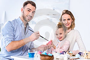 Father and daughter smiling while painting