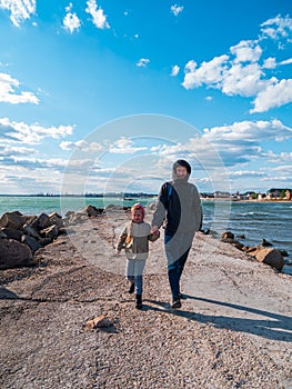 Father and daughter smiling walking running on empty beach. Lifestyle photo real people. Happy active family having fun