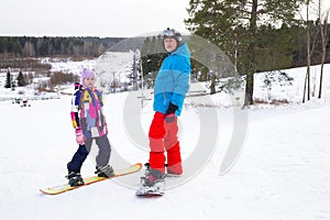 Father and daughter are snowboarding on a snow slope at ski resort