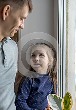 Father and daughter are standing near the window in the kitchen. Time spent together