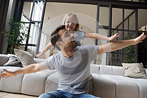 Father and daughter stretched hands play pretend like airplanes