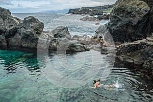 Father and daughter swimming in the natural swimming pool Charco De La Laja, at the north of Tenerife