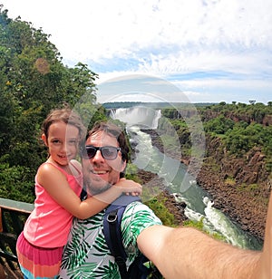 Father and daughter taking a selfie at `IguaÃ§u Falls` on the Brazilian border