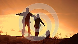 Father and daughter teamwork happy family tourists silhouette concept. team dad and daughter on top of a mountain at