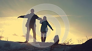 Father and daughter teamwork happy family tourists silhouette concept. team dad and daughter on top of a mountain at