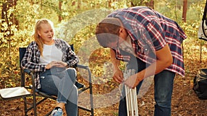 Father and daughter teenager on family picnic in autumn forest. Man preparing table for preparing food at autumn picnic