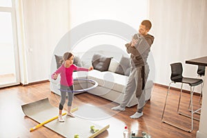 Father and daughter are training at home. Workout in the apartment. Sports at home. she tweaks a hula hoop and dad uses