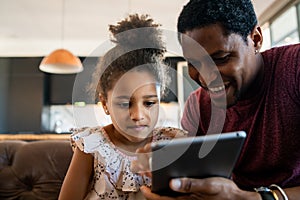 Father and daughter using digital tablet at home. photo