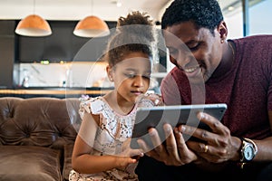 Father and daughter using digital tablet at home. photo