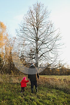 father and daughter walking in autumn forest