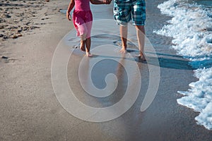 father and daughter walking on beach leaving footprint in sand