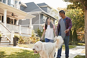 Father And Daughter Walking Dog Along Suburban Street