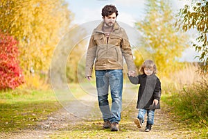 Father and daughter walking together, autumn day.