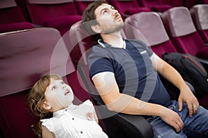 Father and daughter watching film in the movie theater