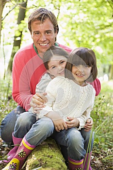 Father and daughters outdoors in woods sitting