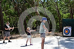 Father and daughters practicing archery together