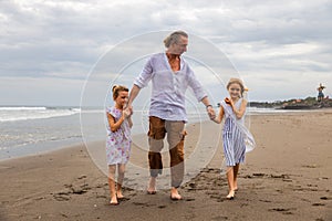 Father with daughters walking barefoot along the beach holding hands. Family relation. Vacation in Asia. Summer holidays. Happy
