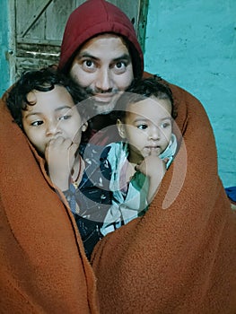 Father and daughters wrapped in blanket
