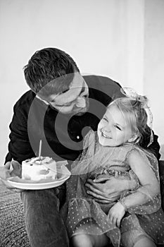 Father and dauther celebrates the birthday of their little daughter. Birthday celebration in dresses with cake.