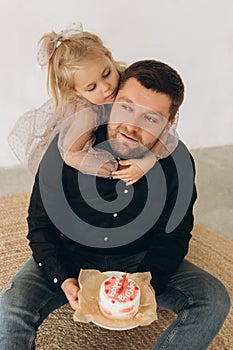 Father and dauther celebrates the birthday of their little daughter. Birthday celebration in dresses with cake.