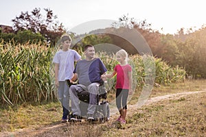 Father with disability and his children walking through natural surroundings photo