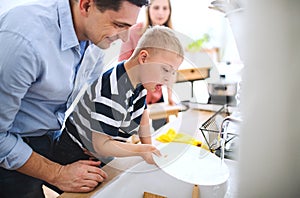 Father with down syndrome son indoors in kitchen, washing dishes.