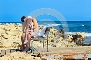 Father embracing and comforting his sad and pouting baby daughter outside on a warm summer day.