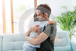 Father embracing son while sitting on sofa