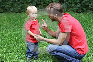 Father emotionally talks with a frustrated child. Upset toddler and his dad. Parenting difficulties concept. Family look clothing. photo