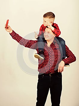 Father example of noble human. Father little son red shirts family look outfit. Taking selfie with son. Child riding on