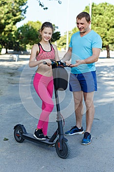 Father explaining daughter how driving kick scooter