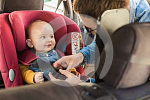 Father fasten his baby in car seat