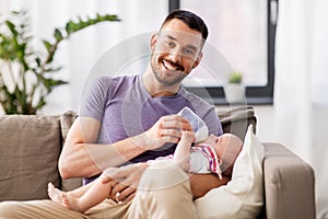 Father feeding baby daughter from bottle at home