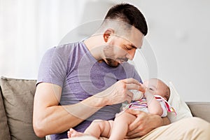 Father feeding baby daughter from bottle at home