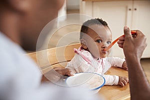 Father Feeding Baby Daughter In High Chair