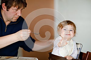 Father feeding baby girl from spoon mashed vegetables and puree. food, child, feeding and people concept -cute toddler