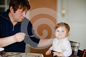 Father feeding baby girl from spoon mashed vegetables and puree. food, child, feeding and people concept -cute toddler, daughter