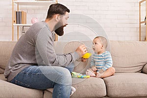 Father feeding his cute baby son at home