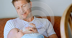 Father feeding milk to his baby boy in living room 4k