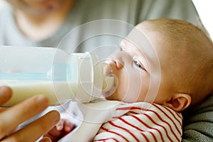 Father feeding newborn baby daughter with milk in nursing bottle