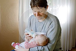 Father feeding newborn baby daughter with milk in nursing bottle